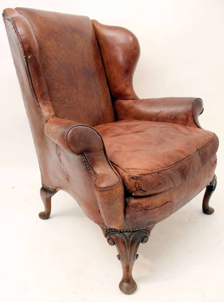 A wonderful late 19th century leather wingback armchair standing on a mahogany cabriole leg.