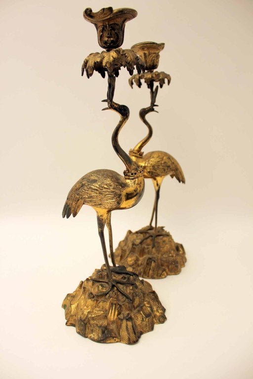 A pair of Victorian gilt and bronze gilded candlesticks in the manner of Thomas Abbott mid 19th century.  The naturalistically cast nozzles and drip pans held aloft by standing figures of cranes on rockwork bases.