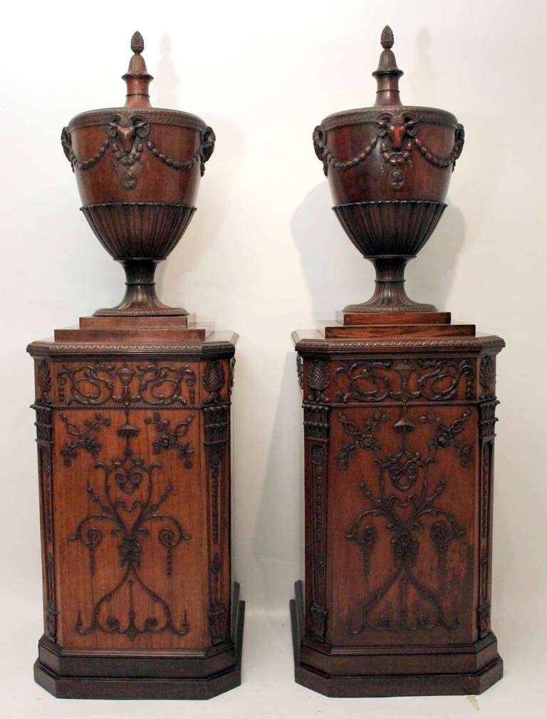 A George III satinwood and carved mahogany dining room pedestal together with a later copy in the manner of Robert Adam

The lidded classical urns with pine-cone finials, one enclosing a lead liner, above ovoid bodies with guilloche borders and