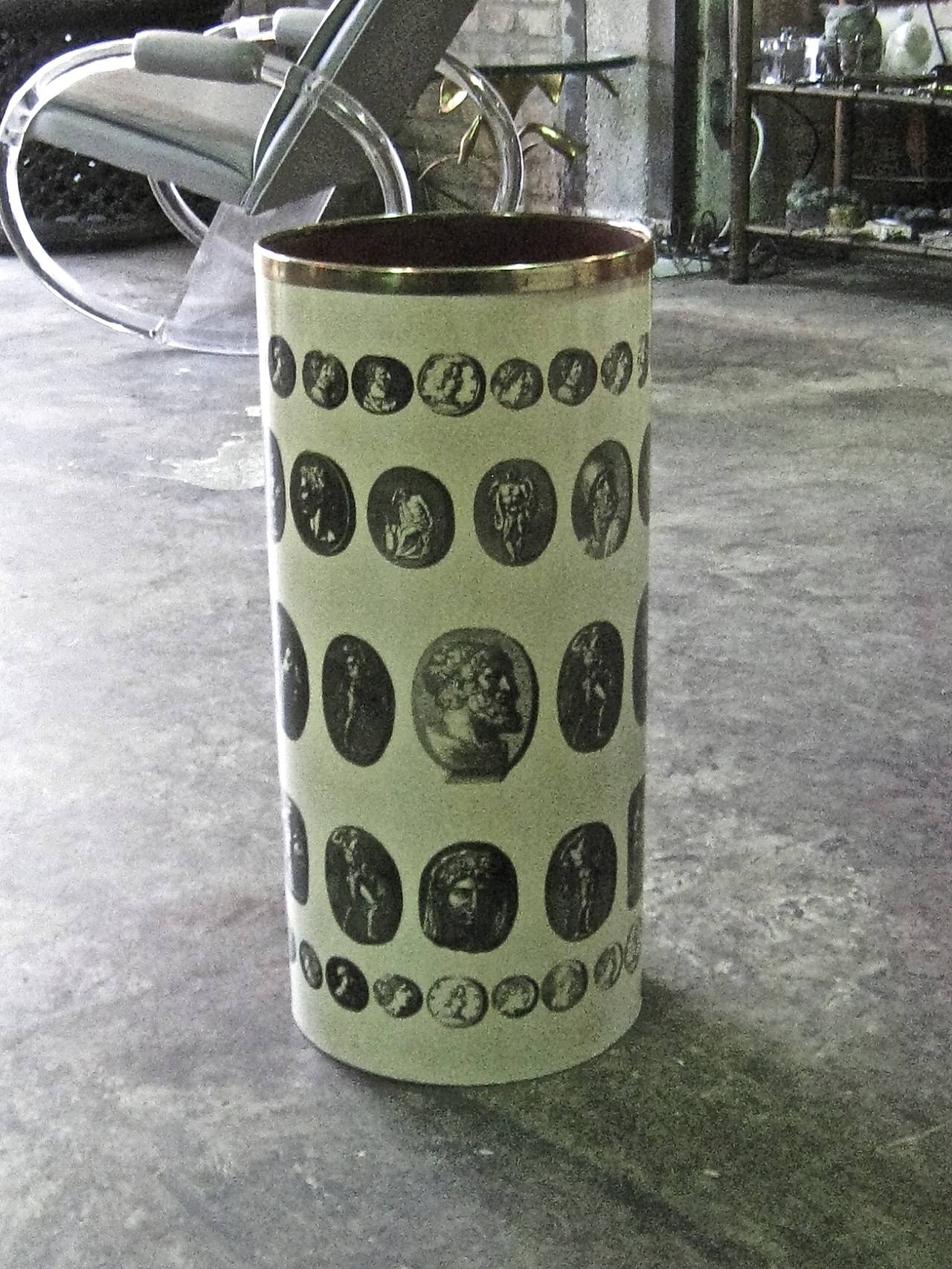 A 1950's metal umbrella stand having a lithographed pattern of neoclassical figures designed by Piero Fornasetti. Original label on underside and interior stamp.