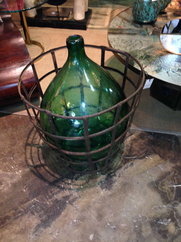Two, 1940s French wine bottles housed in iron baskets.