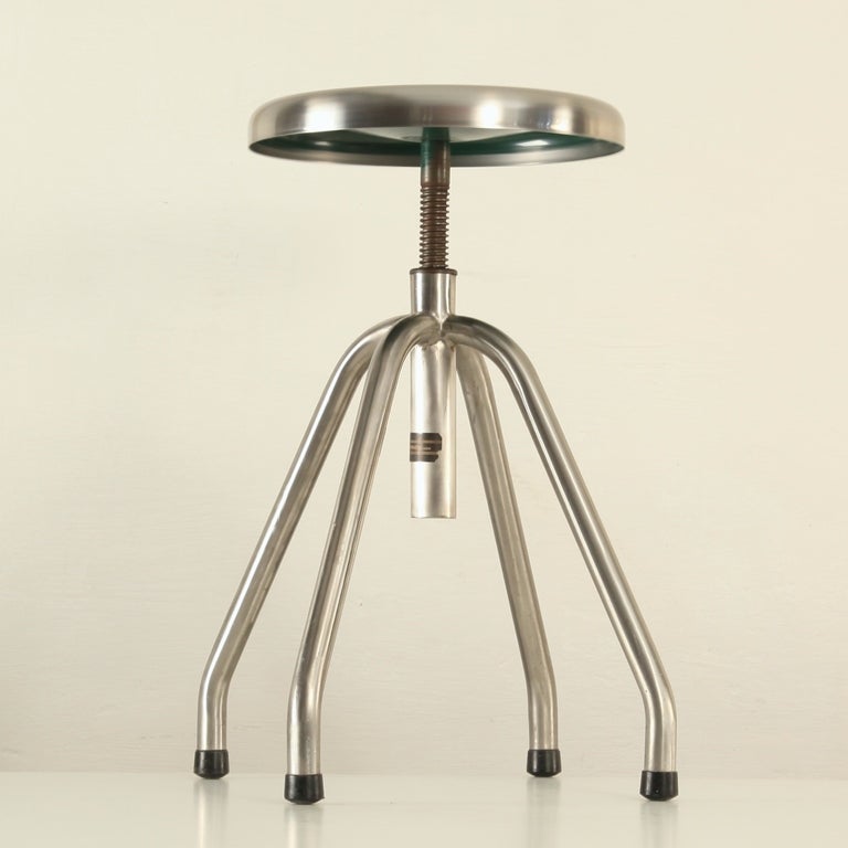 Industrial stool in stainless steel. The seat has a beautiful 
 aged patina.

Perfect to combine with any mid-century table/desk.
Dimensions: 40cm SH:40-50 cm