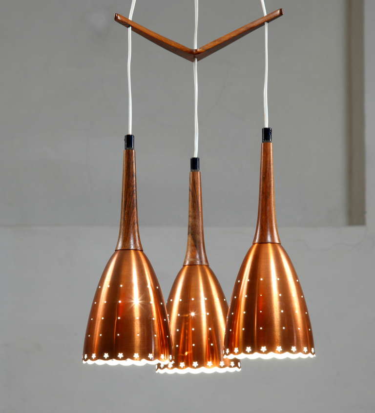 Impressive copper chandelier with performated shades and tropic wood details.
Scandinavian made.Hangingheight of the shades can be changed in any wanted position.
Beautiful piece of Scandinavian lighting in mint condition.
Shades are 37  cm x15 cm