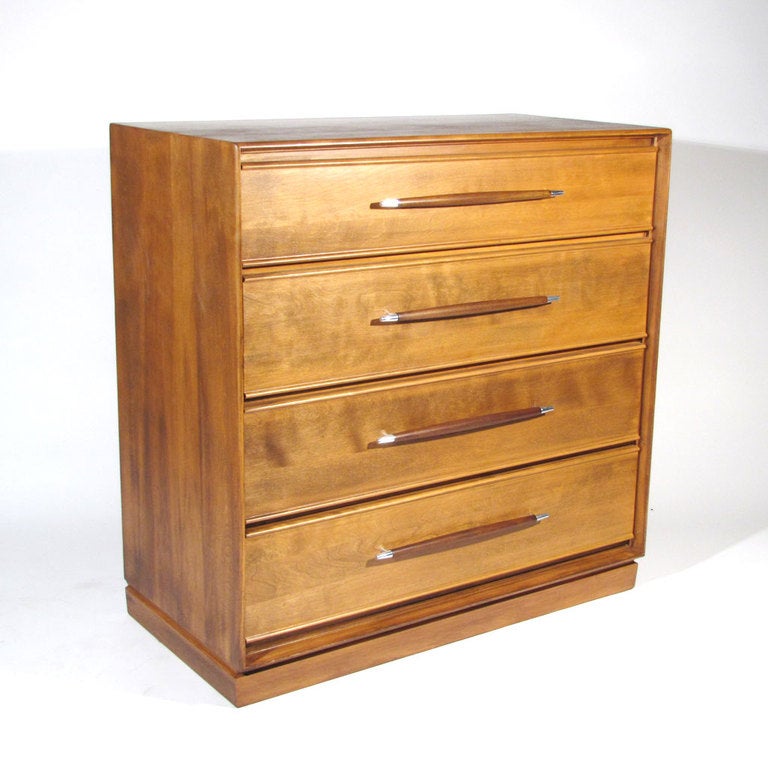 Handsome solid birch four drawer dresser accented with dark spear form walnut pulls with polished chrome tips in the manner of Robsjohn-Gibbings.

Excellent restored condition. Fully refinished with newly polished hardware.