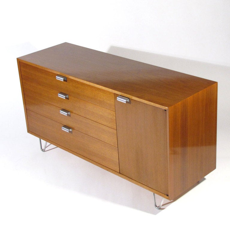 Handsome George Nelson for Herman Miller Model 4713 dresser in walnut with satin aluminum hairpin legs and satin chrome plated J pulls. Four drawers on left with right door revealing a shelved compartment. Foil label affixed. Original finish in