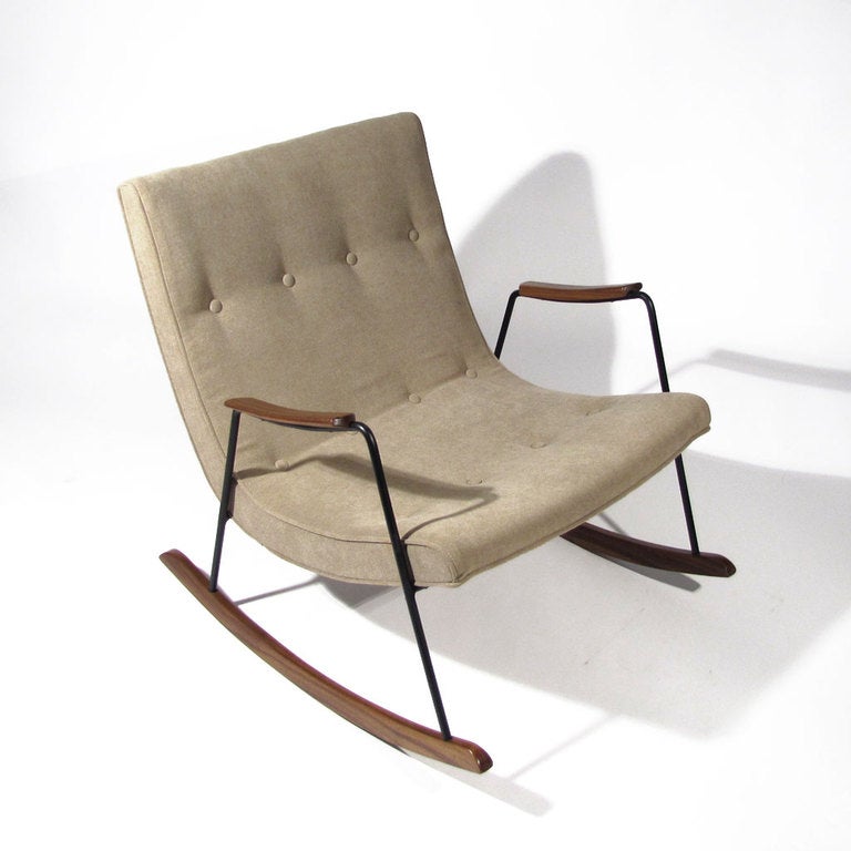 Milo Baughman rocker comprising comfortable scoop seat supported by welded iron frame with walnut arms and rockers. Rare early version produced by Thayer Coggin. Upholstered in soft taupe.

Overall immaculate restored condition. Replaced wood,