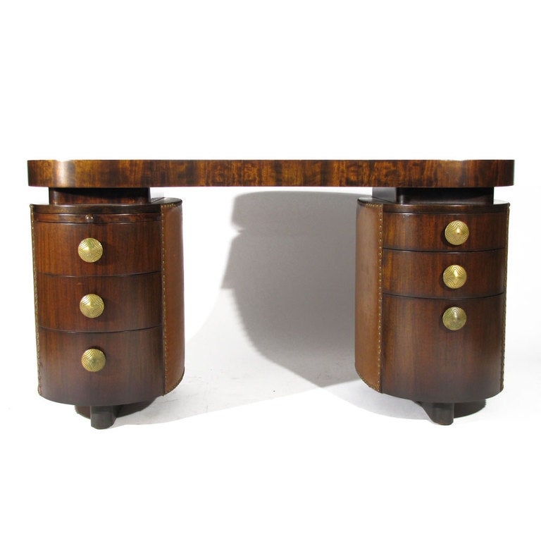 Rare Gilbert Rohde model no. 4115 Paldao double pedestal desk produced by Herman Miller. Biomorphic top with six drawers and pull-out writing surface. Cone brass pulls with Art Deco form and design. Camel leatherette fabric trim with patinated brass
