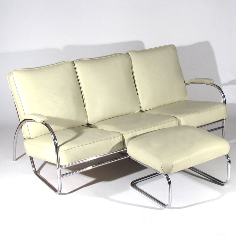 Art Deco Machine Age sofa and ottoman designed by Wolfgang Hoffmann for Howell.  Heavy tubular chrome frames with original spring core wrapped cotton cushions in ivory leather upholstery. From the Gilbert Rohde, Wolfgang Hoffmann, and KEM Weber era