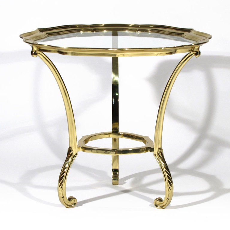 Elegant La Barge brass occasional table. Hand cast heavy solid brass with scalloped border above stationary glass. Beautiful form with curled leaf detailed feet.

Overall excellent condition. No scratches or wear to glass or brass.