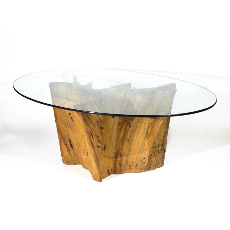 Beautiful vintage exotic wood tree trunk dining table with elliptical glass top. Note the excellent folds of this base which are impossible to accurately capture in photos. Small knots scattered throughout base. Attributed to Michael Taylor.