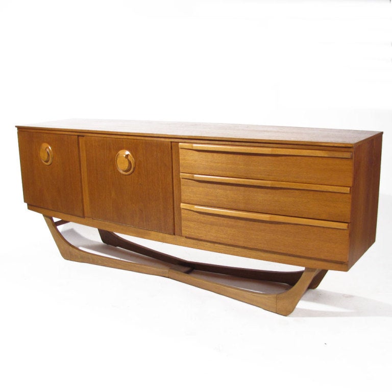 An unusual Danish Modern era walnut sideboard with a center drop down door. Ample storage for a variety of wares with an additional generous left side compartment and three right side drawers. Attractive walnut case accented by sled Adrian Pearsall