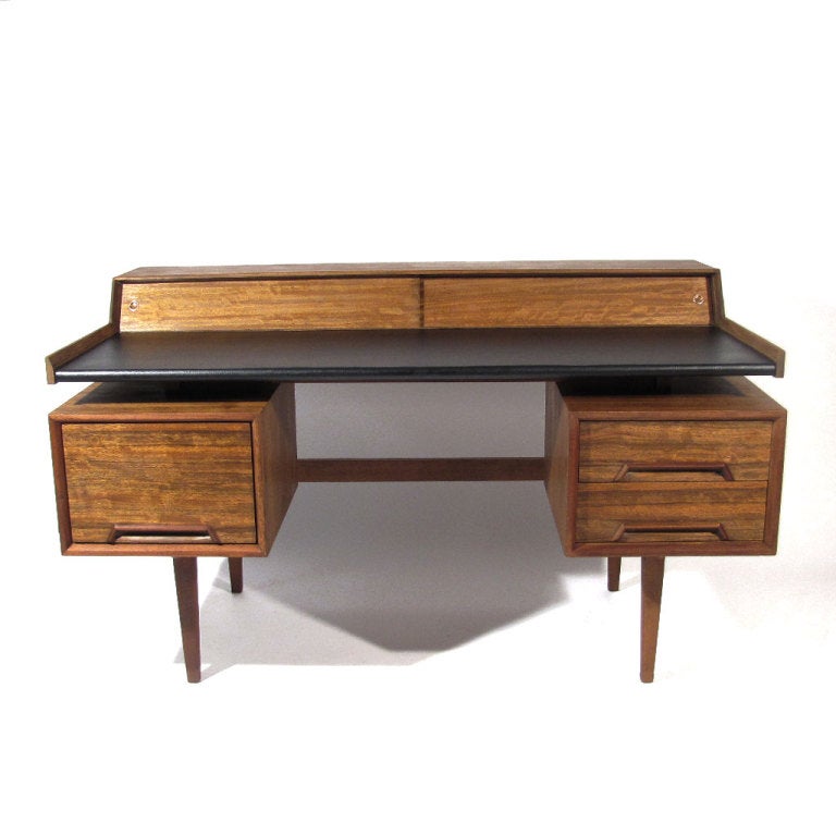 Sleek Milo Baughman floating desk crafted in primavera wood with dramatic ribbon figuring. Left side larger file drawer with two right side smaller drawers, all with recessed long rosewood pulls. Pair forty five degree angled sliding doors with