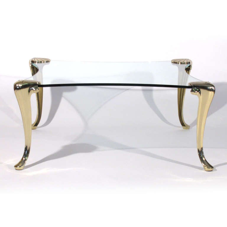 Elegant coffee table crafted by Maison Charles. Gorgeous cabriolet solid brass legs with shell detail top. Convex glass top.

Immaculate restored condition. Polished lacquered brass. New glass.