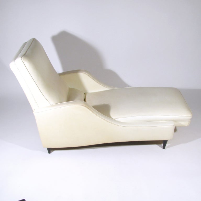 Beautiful chaise lounge resting on black lacquered tapered legs. Upholstered in soft ivory leatherette. Italian Ico Parisi / Gio Ponti influenced form. Exceedingly comfortable.