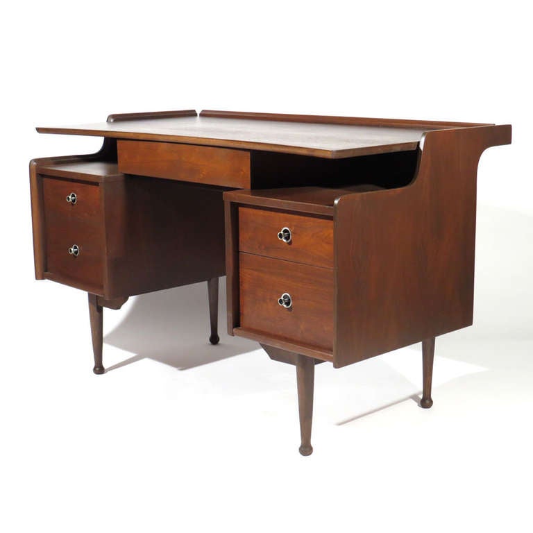 Handsome American Modern floating desk in deep espresso walnut. Two open compartments beneath floating top and above four drawers flanking center drawer. Note concave top with raided edges.

Excellent restored condition.