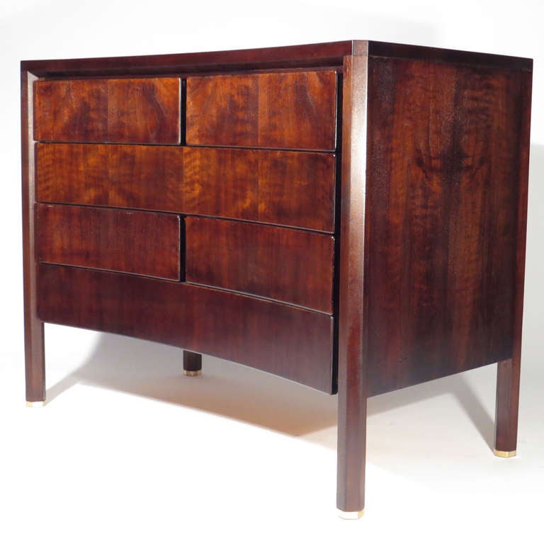 Handsome Edmond Spence six drawer bachelor's chest. Deep espresso glaze over flame walnut. Concave form with hexagonal legs and brass sabots. Depth slopes from 22