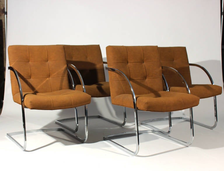 Set of four Milo Baughman dining chairs. Feature cantilevered chrome frames. Upholstery is a caramel-tan colored faux suede. Chrome is in very good vintage condition. Upholstery is in good vintage condition with only slight signs of wear.