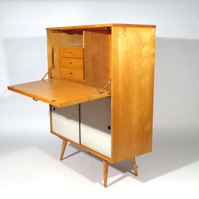 Rare Paul McCobb maple secretary from the Planner Group. Beneath two lacquered eggshell doors reveal a generous storage compartment with positionable shelf. Top opens to provide a sizable work surface with three small drawers beneath a small open