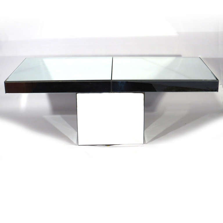Sleek Ello mirrored dining table with two skirted leaves. Sides of table are siver mirror, although they appear black in photos due to reflection. 72 inches long without leaves. Two 18 inch leaves.