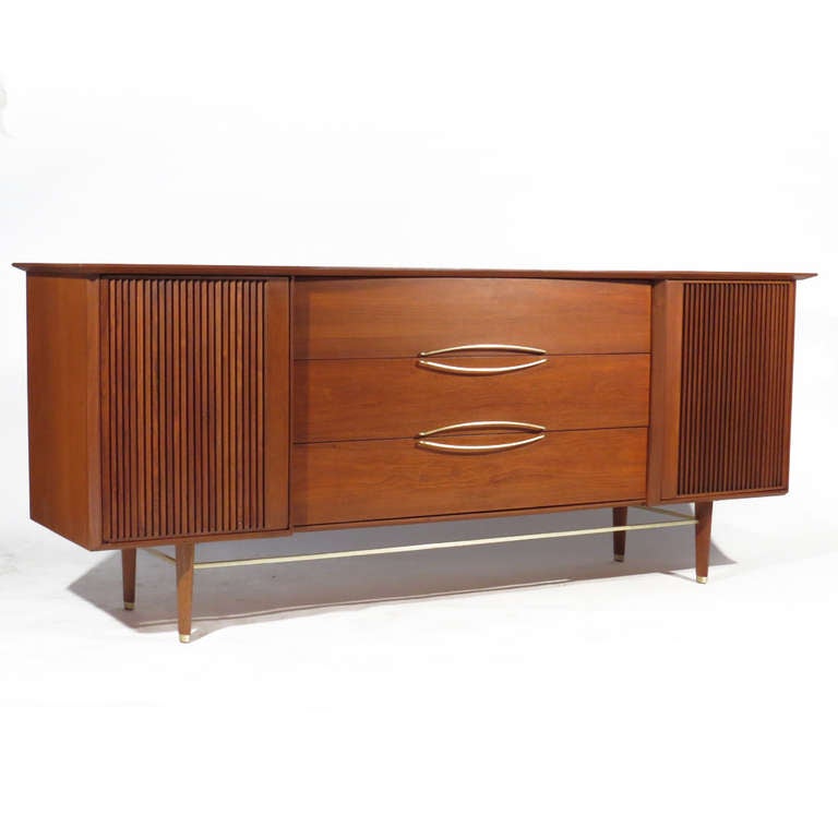 Streamlined Hobey Helen for Baker walnut dresser with three central drawers, flanked by grooved doors, each revealing three interior drawers. Brass stretchers, pulls, and sabots. Excellent restored condition.
