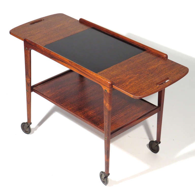 Danish rosewood drop leaf serving cart designed by Tove Kindt-Larsen. Rosewood leaf flips with ease to increase top size. Brass hardware. Deep rosewood color with gorgeous figuring.