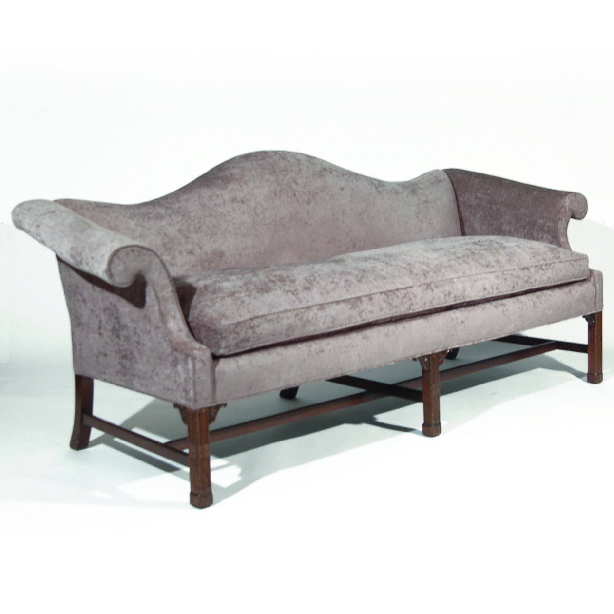 Camel back Chippendale style sofa with mahogany frame from first half of the 20th Century. Chippendale design on chamfered square legs with cross stretchers and topped with scroll carvings. Newly upholstered in Valencia-Titanium a quality 