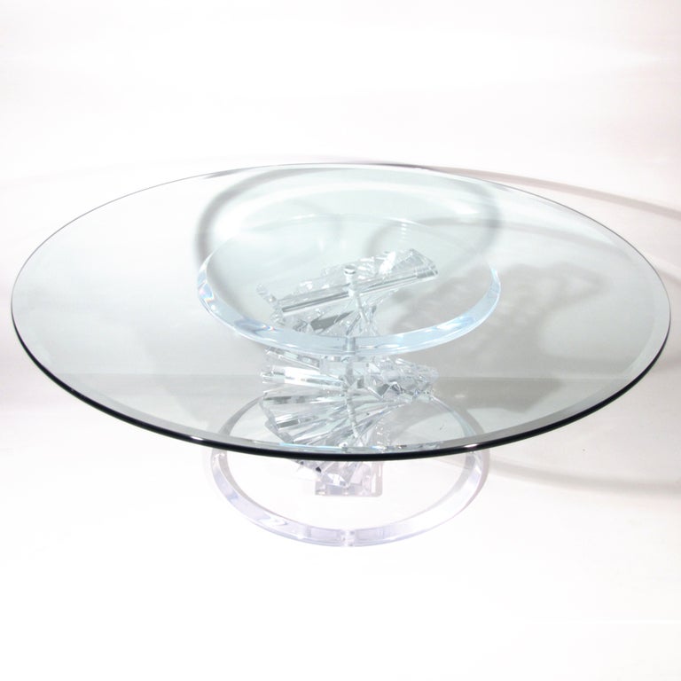 Striking helix form base Lucite cocktail table with thick stacked Lucite panels twisting in between two round beveled discs, supporting round beveled glass top.

Glass free of issues. Professionally polished Lucite. Please call Stacey for a