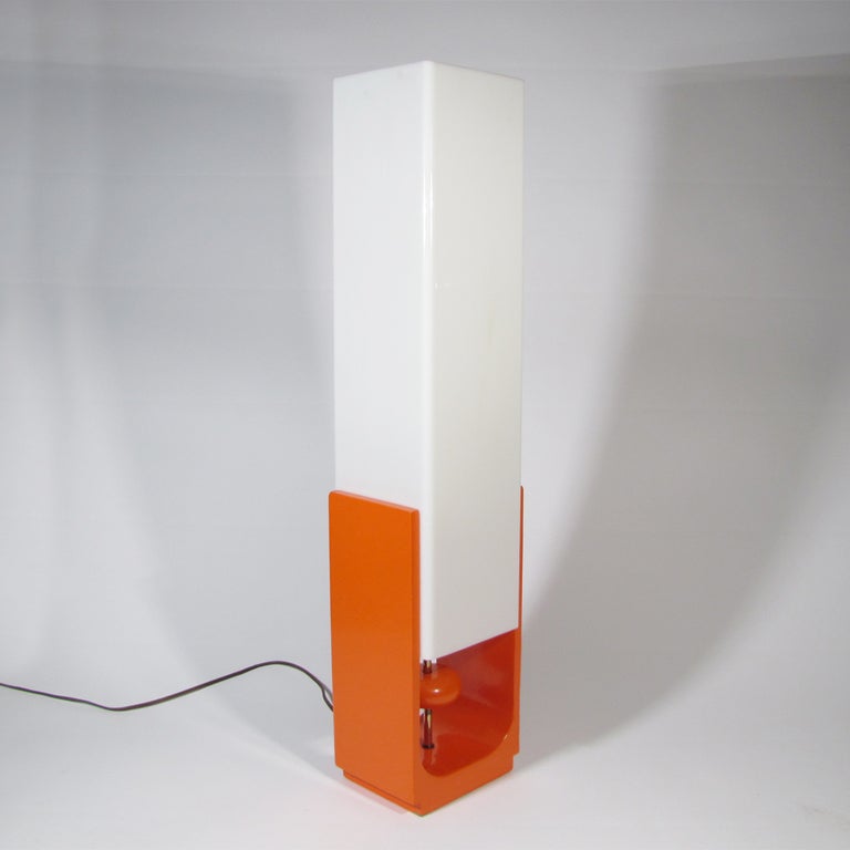 A wonderful unique 60's tall table or low floor lamp with orange lacquered base. It features a yoyo form pull on a central brass stem. Simply depress the yoyo, and the light switch is engaged on or off, and the yoyo raises back into position. Thick
