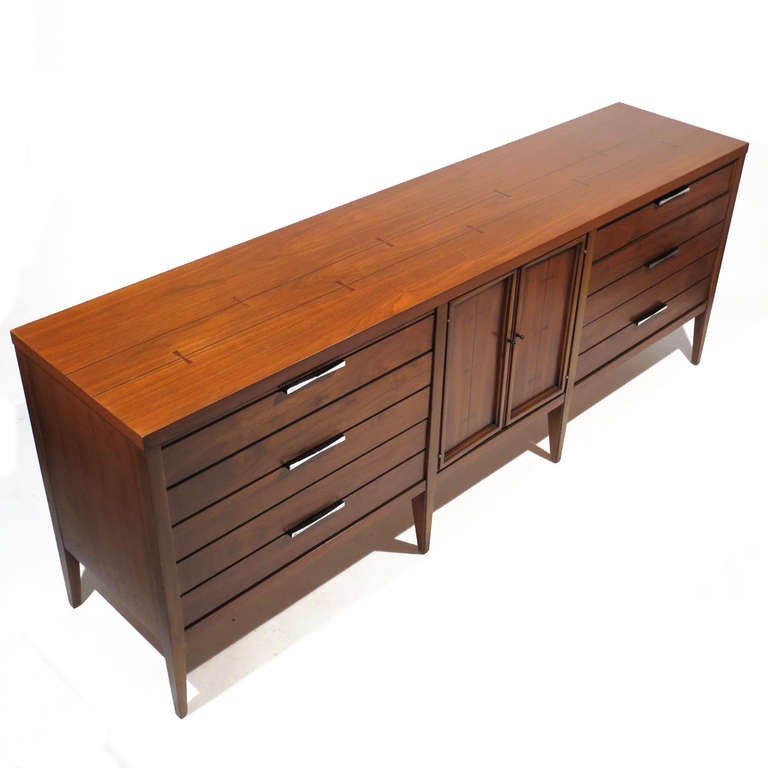 Handsome Mid-Century long nine drawer dresser in walnut with rosewood bow tie and ebony pinstripe inlay. Matching cast aluminum pulls. Superb restored condition. From the Tuxedo line.