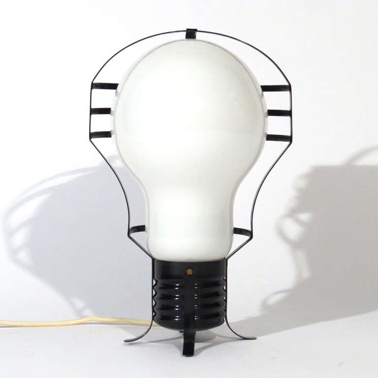 Unusual Mid-Century table lamp. Welded black steel cage encloses enormous hand blown white light bulb form globe.