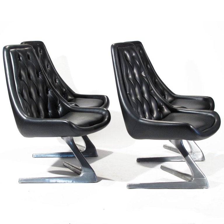 Cool set of four Chromcraft dining chairs upholster in black. These are the harder to find plain seat version. Polished aluminum V form swivel bases.  In the manner of the Vladimir Kagan Unicorn chair, this particular model was used in early Star