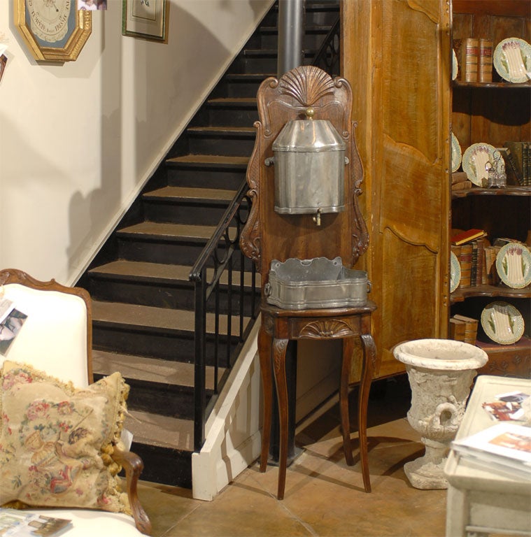 Ein französisches Lavabo aus Zinn aus der Zeit Ludwigs XV. auf einem Ständer aus Nussbaumholz aus dem 18. Jahrhundert, mit handgeschnitzten Muschelmotiven und Voluten. Dieser elegante Brunnen, der in Frankreich während der Herrschaft von König