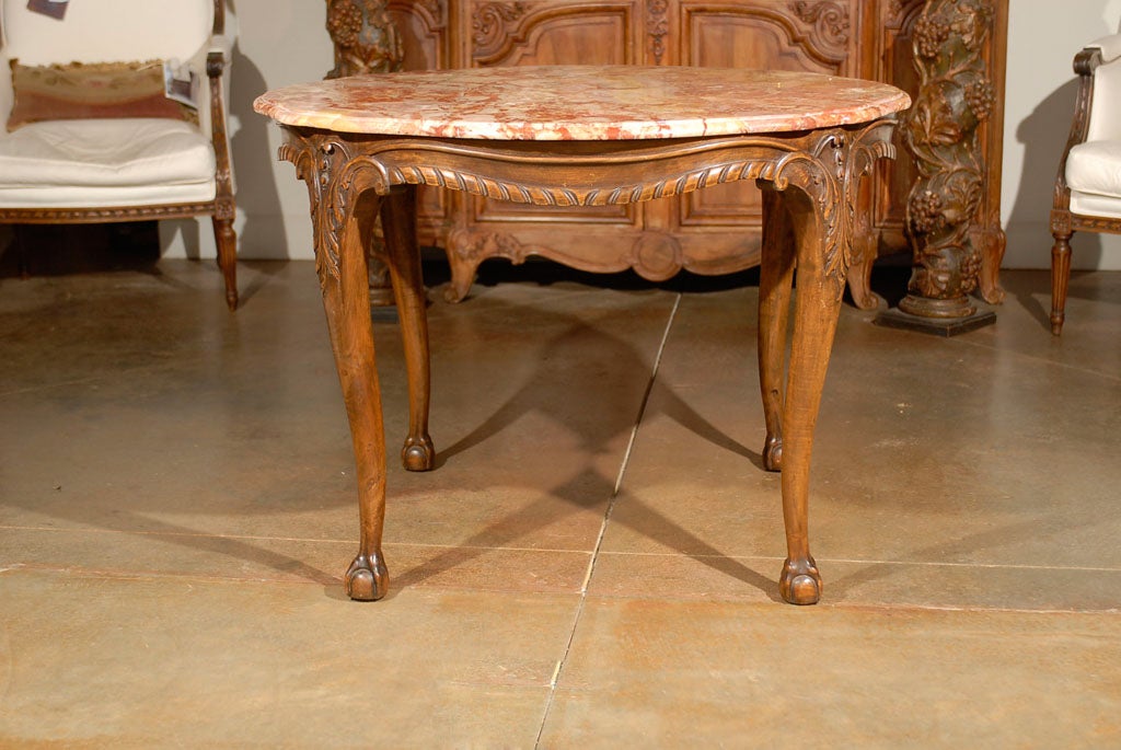 A French carved walnut center table from the 19th century, with variegated marble top, twisted ribbon molding and ball-and-claw feet. This exquisite French center table features its original variegated circular marble top with serpentine accents,