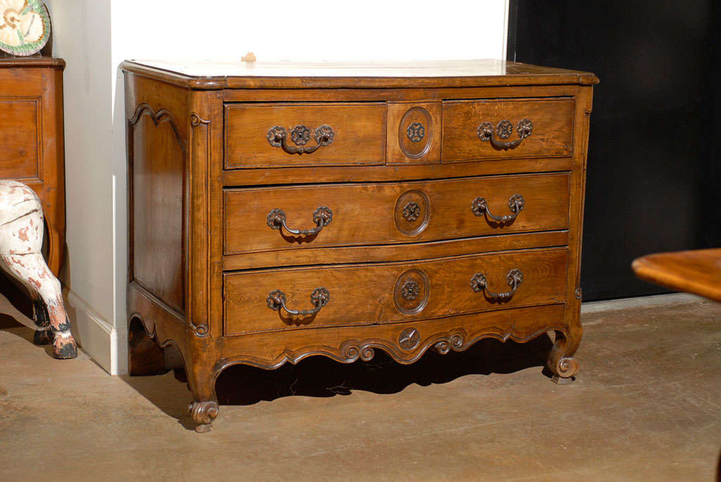 A French Louis XV period walnut four-drawer serpentine commode from the 18th century, with scalloped skirt and star motif. Born in France during the reign of king Louis XV, this exquisite walnut commode features a rectangular planked top with