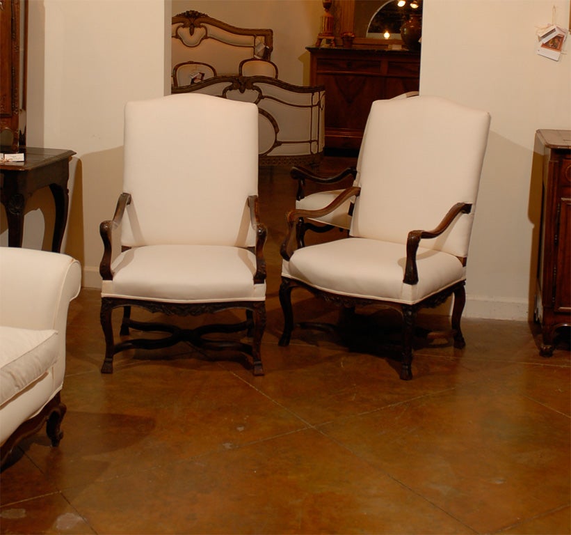 A pair of French Régence style wooden armchairs from the mid-19th century, with Saint-Andrew style cross stretchers, hoofed feet and upholstery. We currently have two pairs available. Born in France in the early years of Emperor Napoleon III's