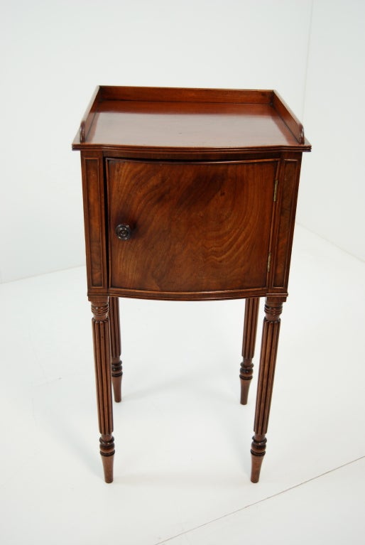 Georgian mahogany bow fronted bedside cupboard, with tray top, on turned and fluted legs.