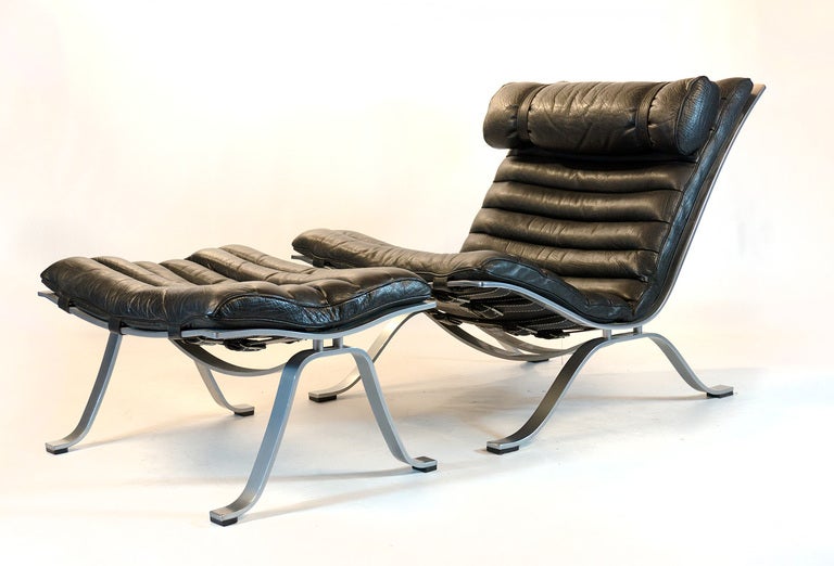 Beautiful Ari lounge chair with matching ottoman.

Designed by Arne Norell for Norell Mobler Sweden.
In brushed steel; heavy leather straps for support and buffalo leather upholstery.
 
Designed in 1966. 
A striking piece with extreme