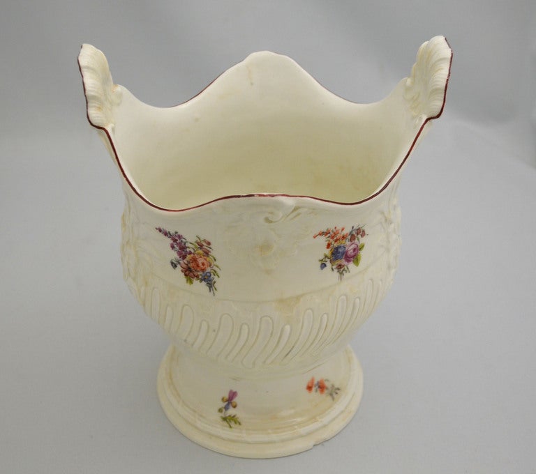 A rococo moulded wine cooler decorated with scattered flowers beneath a dark red rim and an imitation of Meissen. Mark on bottom is a red anchor. The red anchor period of Chelsea spanned from 1752 to 1756 and was influenced by Japanese pottery, as