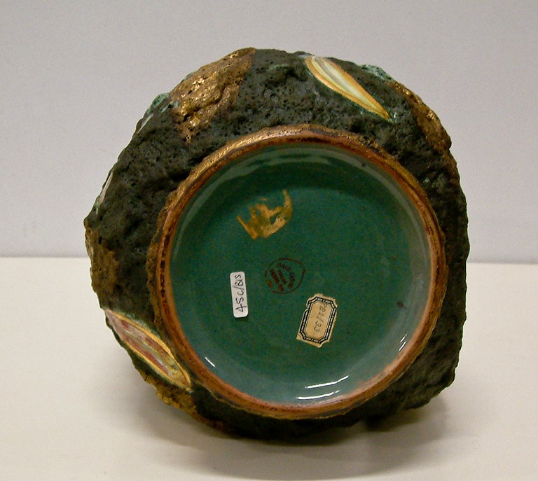 A large volcanic lava glaze ewer with colorful stylized banana and peacock feather-like forms in high glaze.  This heavily textured piece has the maker's stamp and a paper inventory label on the base.