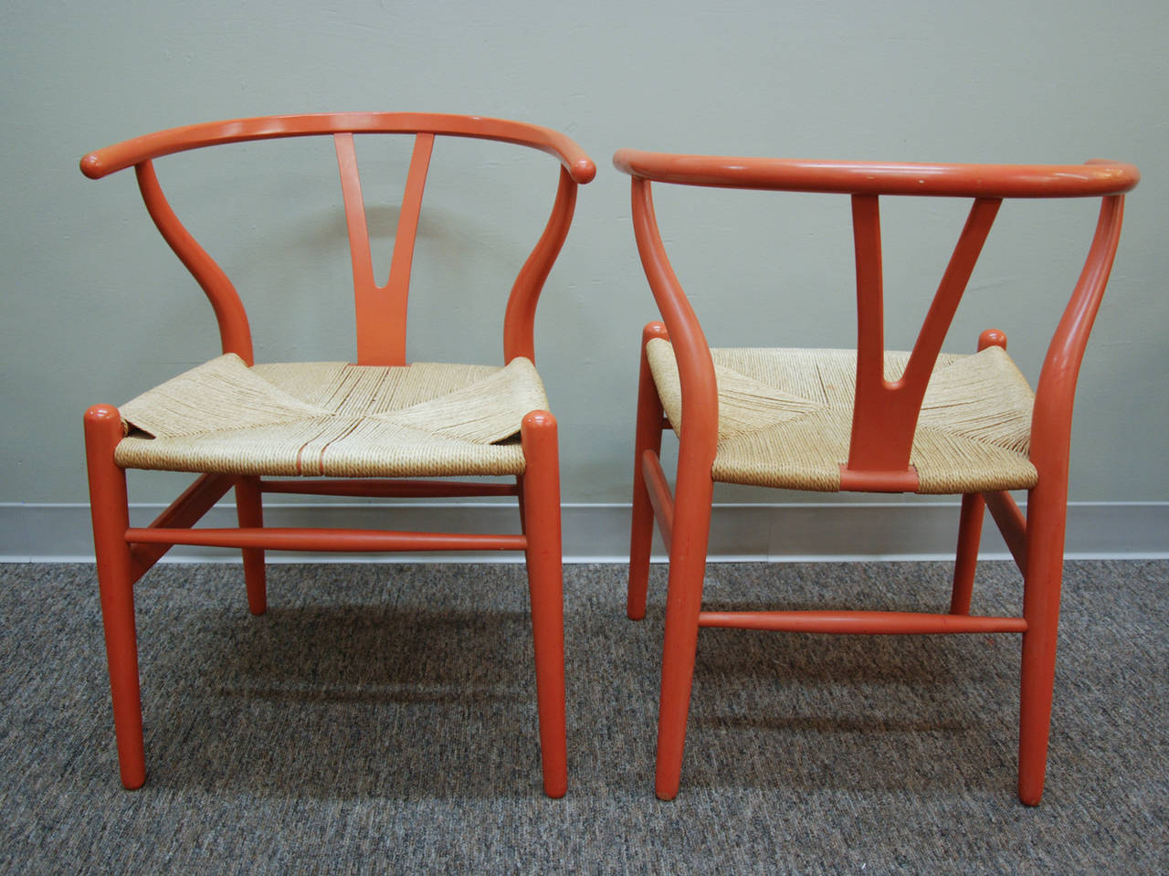 A classic pair of early production CH-24 wishbone chairs designed by Hans Wegner and manufactured by Carl Hansen & Son in the original and rare salmon lacquered finish with the original paper cord seat.  The chairs are often referred to as the Y