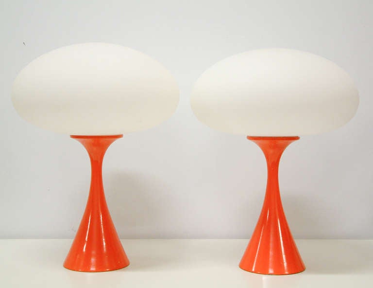 A Classic pair of enameled steel and frosted glass lamps in the original orange paint finish. One of the rarest and most desirable colors and signed with the original Laurel manufacturer's label to the metal diffuser.