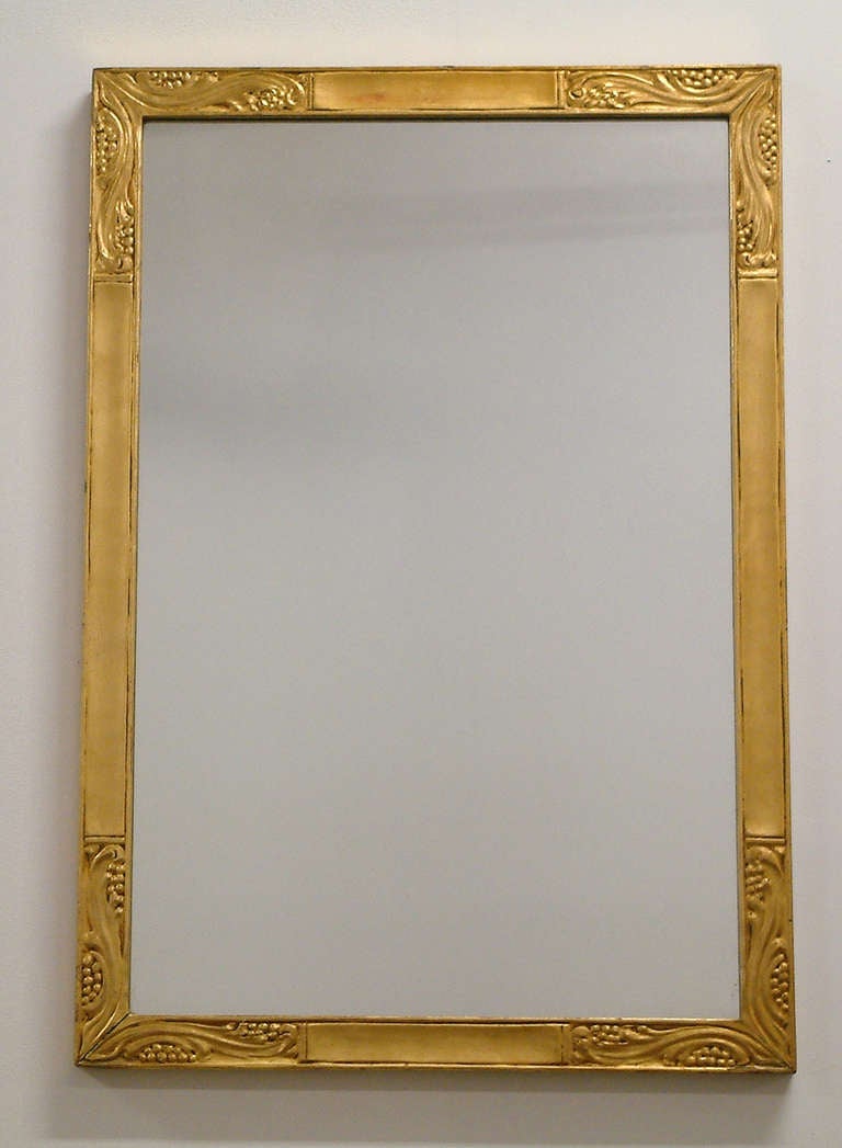 A beautifully carved and gilded Art Nouveau inspired mirror with a organic leaf and berries motif with the original mirrored glass. Continental.