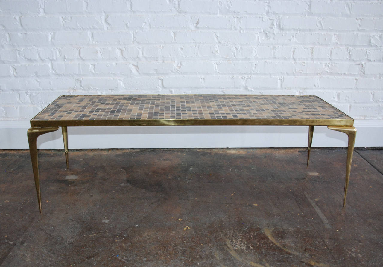 A very sleek brass and Murano glass tile top table designed in Italy.  The brass legs are cast in Japan and stamped on the underside.  This design is often attributed to Gio Ponti and is a good example of streamlined Mid Century Italian design.