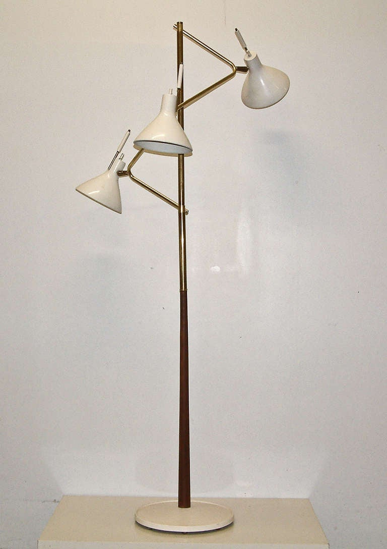 A stunning Lightolier brass, walnut and polychromed aluminum lamp with three adjustable pivotal shades that rotate 360 degrees. This is a very early and rare Lightolier design with a lathed walnut shaft.
