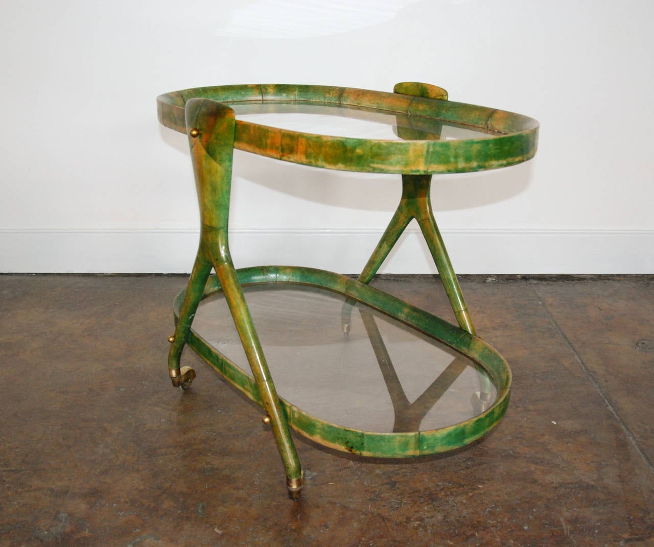 A beautiful green parchment Aldo Tura barcart with two oval glass shelves and brass fittings.  Excellent Condition.