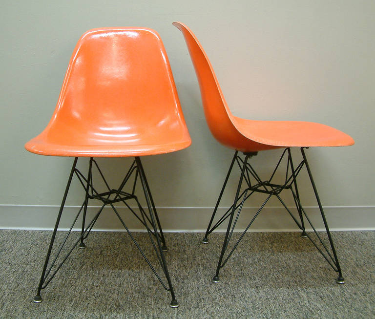 A fine pair of orange fiberglass side chairs designed by Charles and Ray Eames for Herman Miller in 1950. The chairs have the second edition 