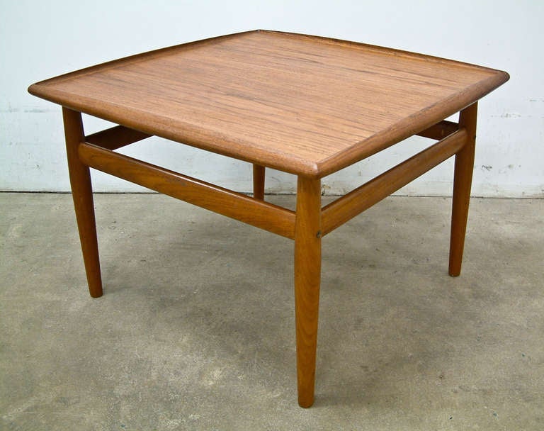 A teak and brass square coffee table by award winning Danish designer Grete Jalk.  In 1953 she won the Georg Jensen competition and established her design firm the following year.  In 1956 she became co-editor of the Danish design journal Mobilia