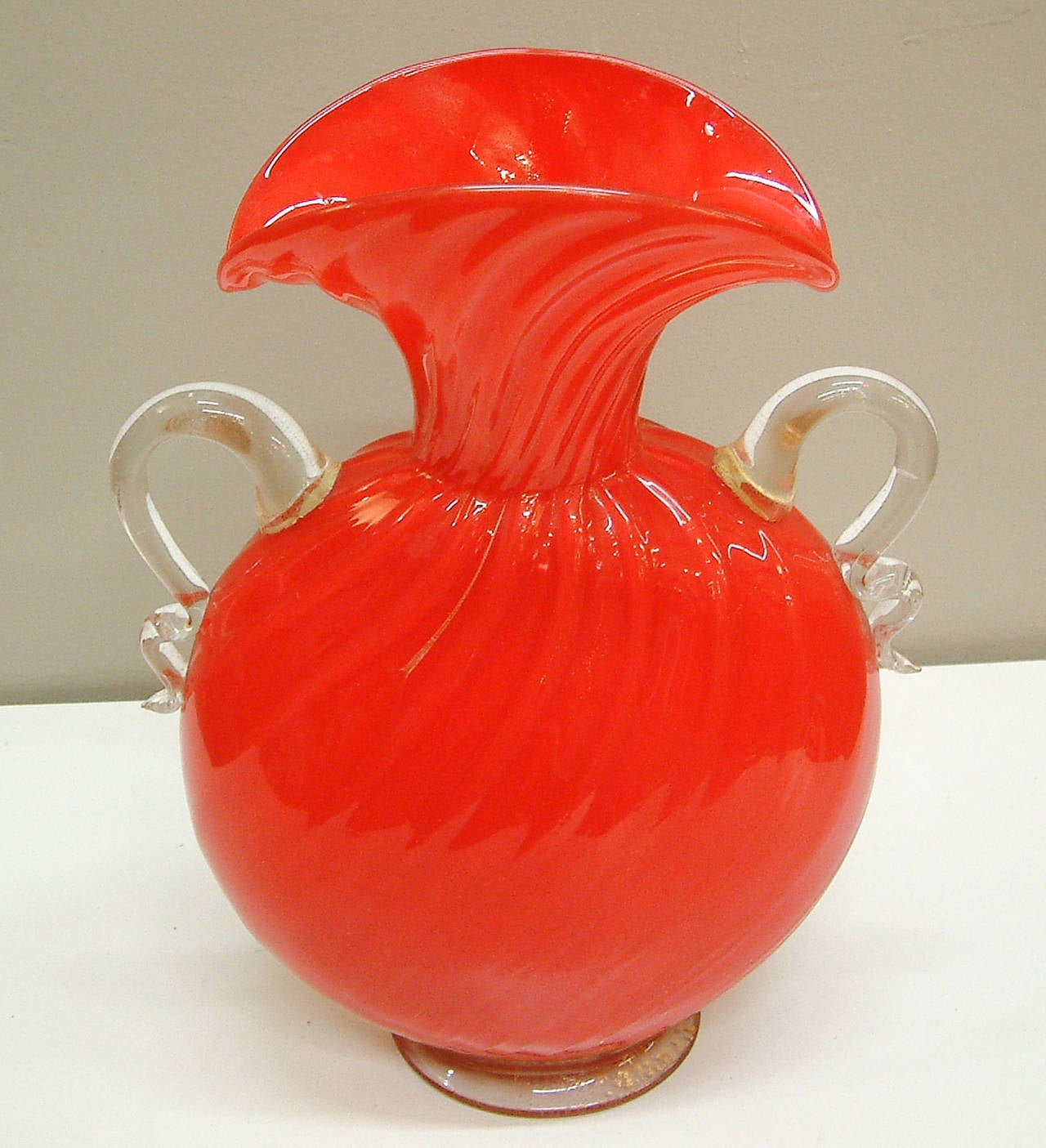 A large and fine red glass pillow form footed vase with expanded gold leaf and serpentine handles similar to examples by Barovier and Toso.  The vase is acid stamped made in Italy on the pontil.  For a similar example of this model reference Sollo