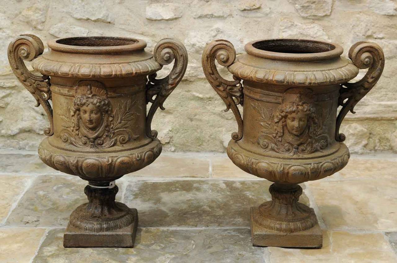 A rare pair of cast iron vases dated late 19th Century ornated with masks. One has been restored. Durenne Foundry. Base : 7 in. # E5654