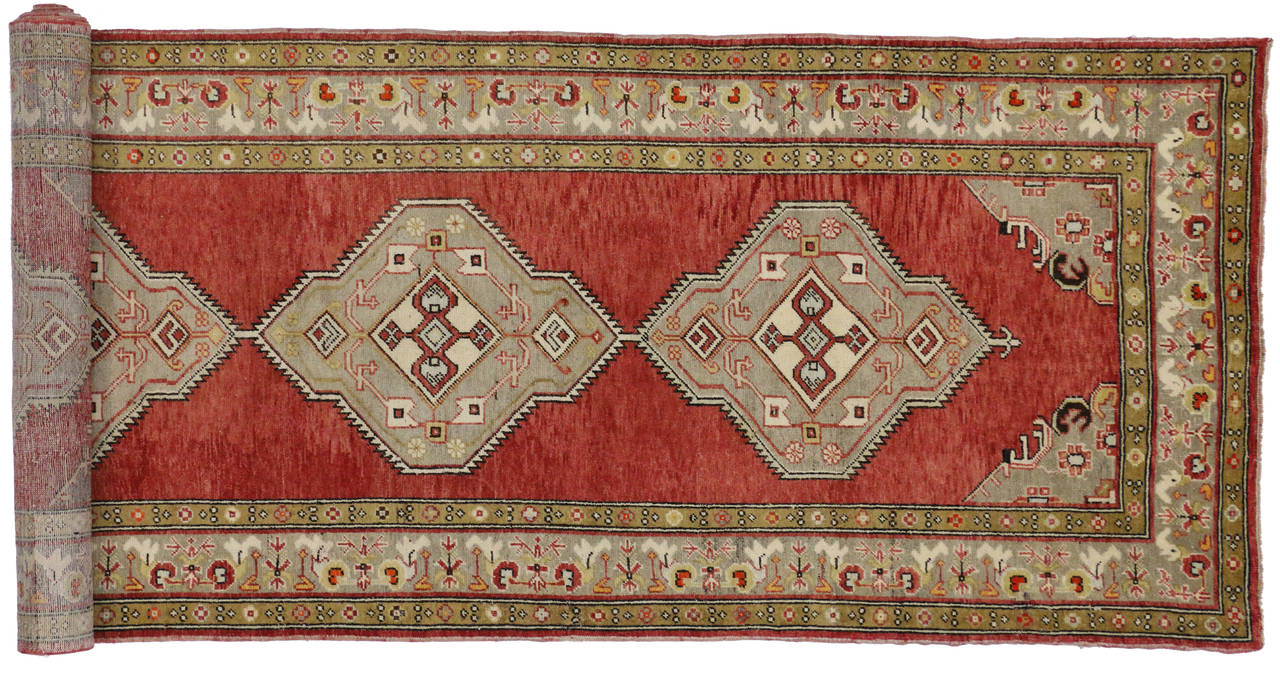 This remarkable Oushak carpet runner was hand-knotted in Turkey's famed Ushak region. It features a powerful geometric pattern rendered in an energetic combination of red, soft green and turmeric yellow with hints of ivory and defining black